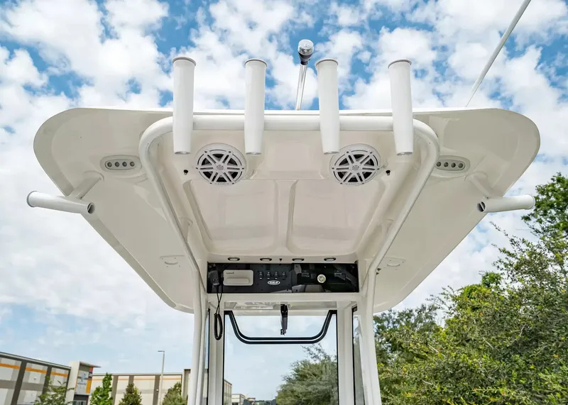Slide: The Image of The image shows the T-top of a 2027 Sea Hunt BX25FS boat with speakers and rod holders. - 11