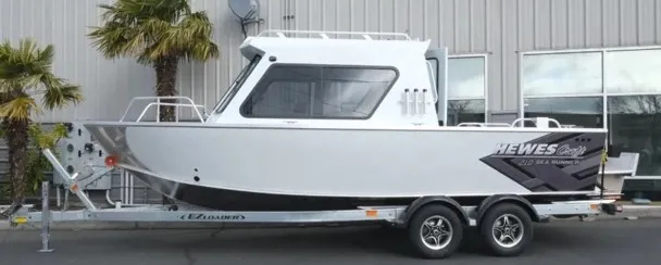 The Image of A white boat with a hard top sits on a trailer in front of a building. - 2