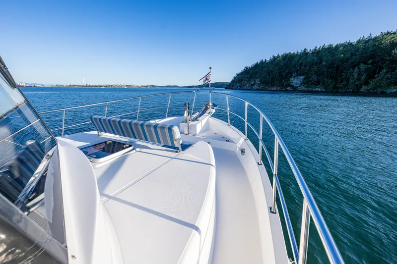 Slide: The Image of 2023 North Pacific 53 Euro yacht cruising on serene waters near a forested shoreline. - 64