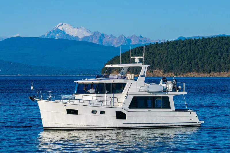 Slide: The Image of 2023 North Pacific 53 Euro yacht cruising on scenic blue waters with mountains in background. - 88