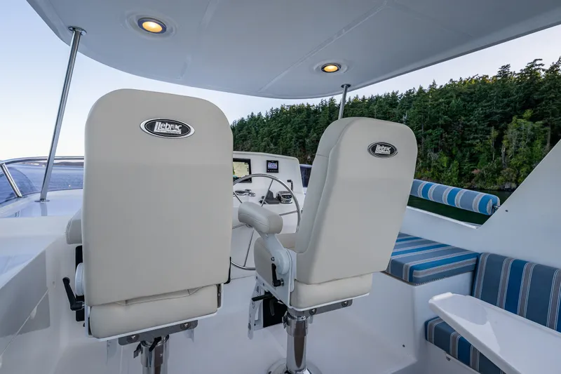 Slide: The Image of 2023 North Pacific 53 Euro yacht helm with white seats and scenic forest backdrop. - 55