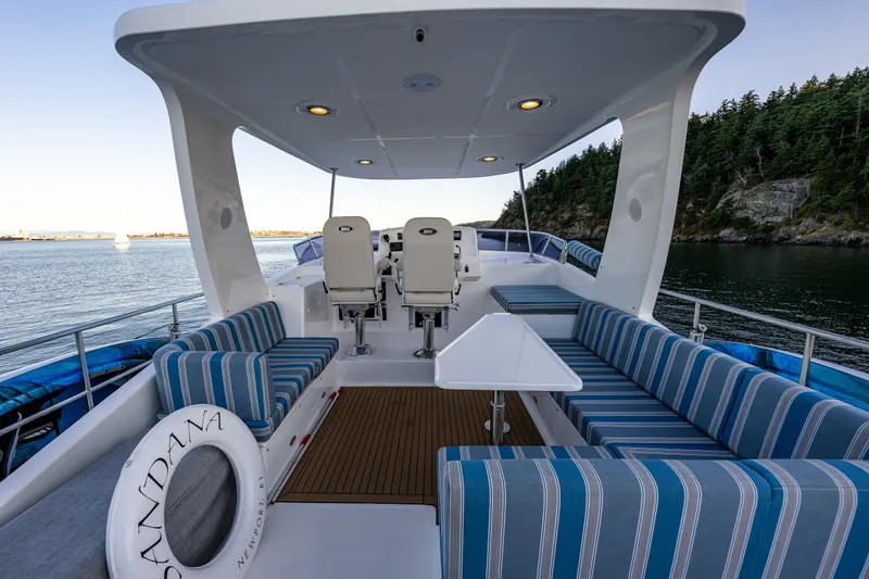 Slide: The Image of Luxurious 2023 North Pacific 53 Euro yacht deck with striped seating and scenic water view. - 52