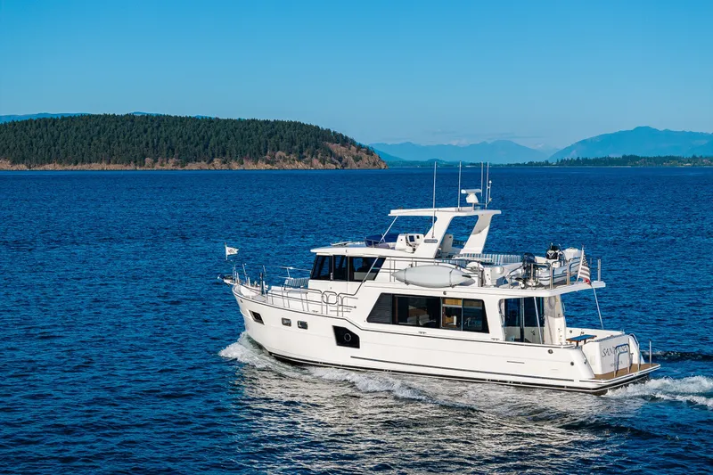 Slide: The Image of 2023 North Pacific 53 Euro yacht cruising on a serene blue sea with forested islands. - 104