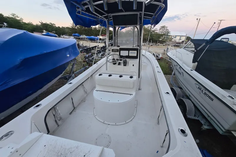 Slide: The Image of 2015 May-Craft 2300 CCX boat with blue canopy, docked among other boats. - 17