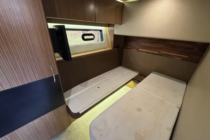Slide: The Image of 2016 Sea Ray L590 yacht cabin interior with wooden finishes and a cozy bed setup. - 26