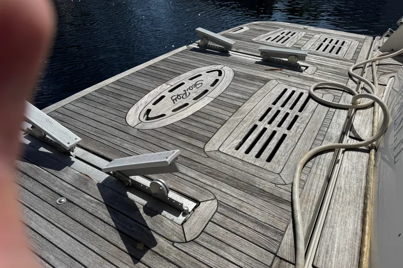 Slide: The Image of 2016 Sea Ray L590 yacht deck with wooden finish and cleats, docked by water. - 13