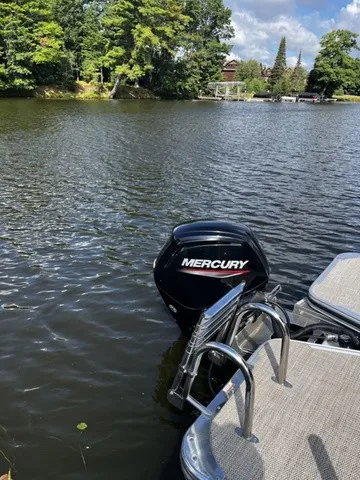 Slide: The Image of A Mercury outboard motor on a pontoon boat on a calm lake with wooded shoreline. - 18