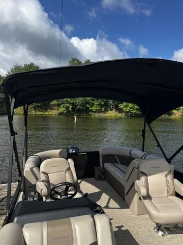 Slide: The Image of A modern pontoon boat with beige seating and a black canopy, on a calm lake. - 3