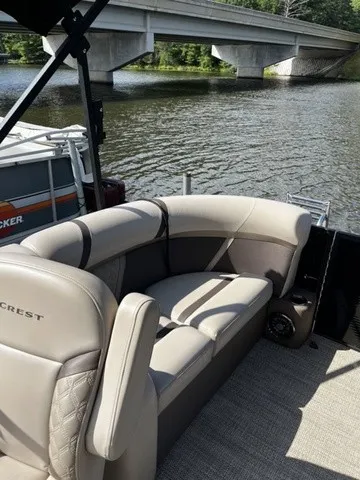 Slide: The Image of A sleek pontoon boat with beige seating, situated on a calm river under a bridge. - 15