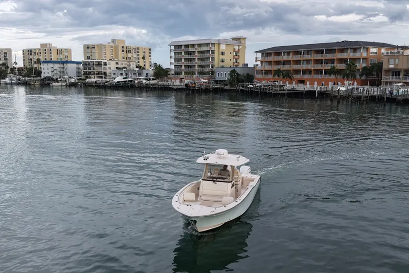 Slide: The Image of 2021 Grady-White Canyon 326 boat cruising near waterfront buildings under cloudy sky. - 37