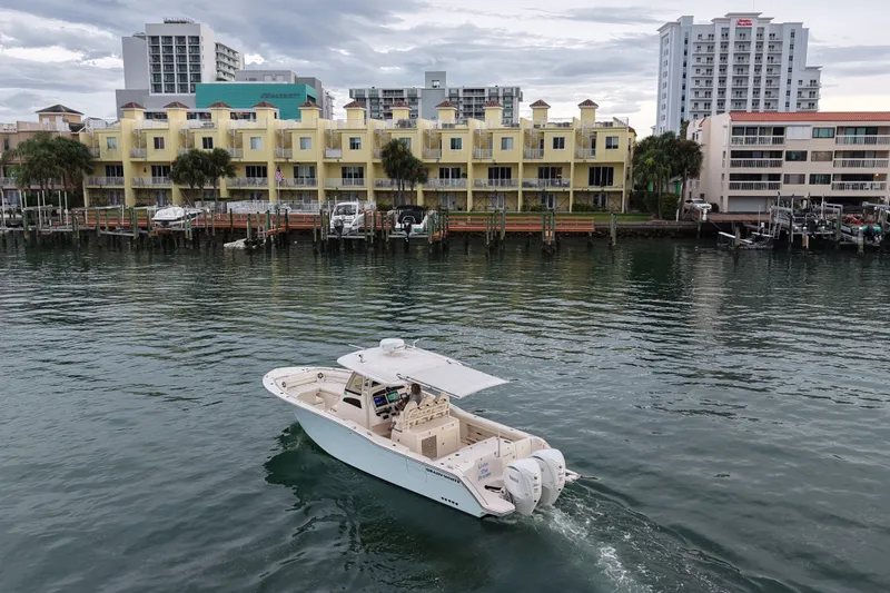Slide: The Image of 2021 Grady-White Canyon 326 boat cruising near waterfront buildings. - 28