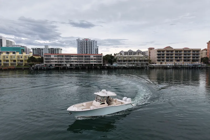 Slide: The Image of 2021 Grady-White Canyon 326 boat cruising near waterfront buildings under cloudy sky. - 13