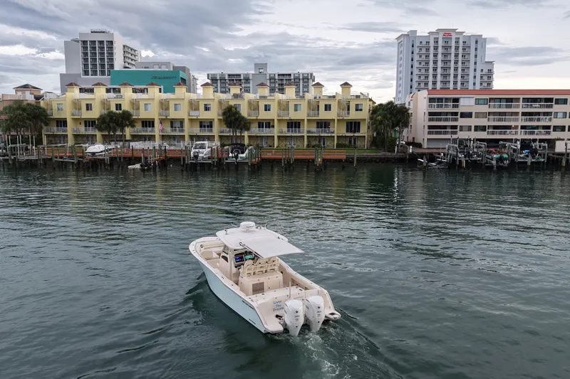 Slide: The Image of 2021 Grady-White Canyon 326 boat cruising near waterfront buildings. - 31