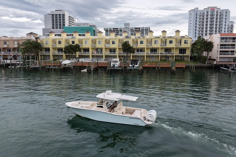 Slide: The Image of 2021 Grady-White Canyon 326 boat cruising near waterfront buildings. - 26