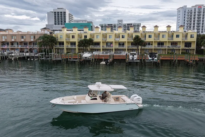 Slide: The Image of 2021 Grady-White Canyon 326 boat cruising near waterfront buildings. - 25