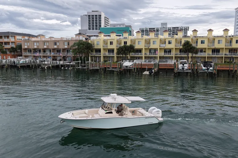 Slide: The Image of 2021 Grady-White Canyon 326 boat cruising near waterfront buildings. - 22