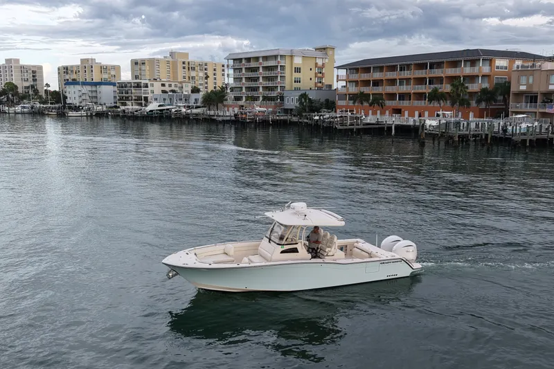 Slide: The Image of 2021 Grady-White Canyon 326 boat cruising near waterfront buildings under cloudy sky. - 39