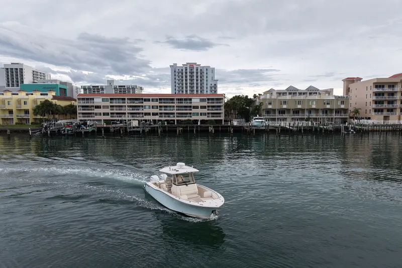 Slide: The Image of 2021 Grady-White Canyon 326 boat cruising near waterfront buildings under cloudy sky. - 19