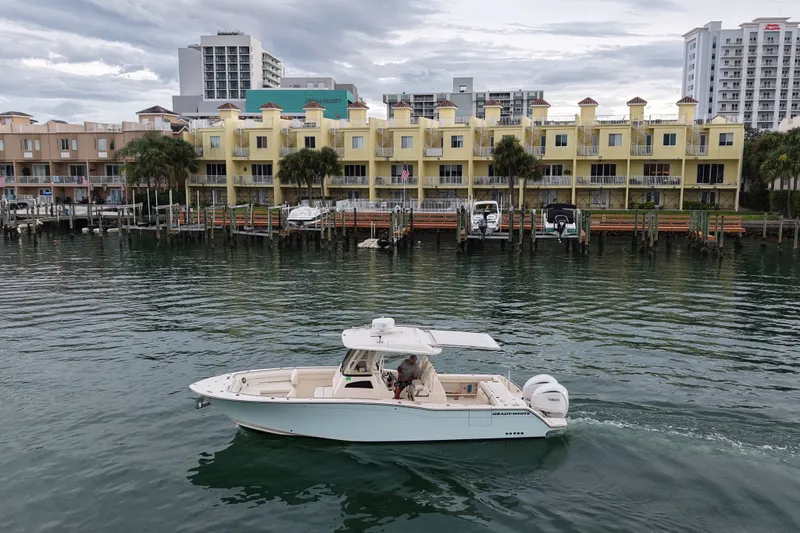 Slide: The Image of 2021 Grady-White Canyon 326 boat cruising near waterfront buildings. - 24