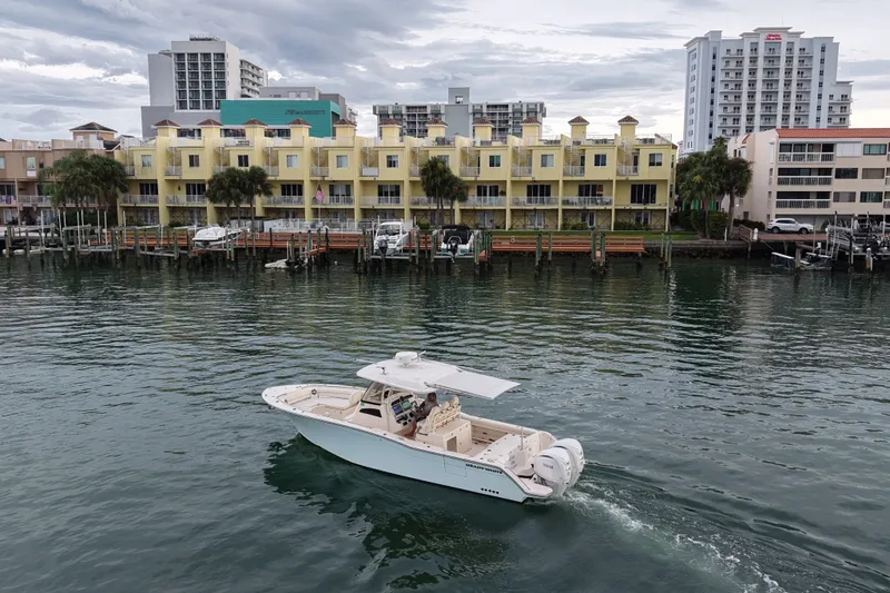 Slide: The Image of 2021 Grady-White Canyon 326 boat cruising near waterfront buildings. - 27