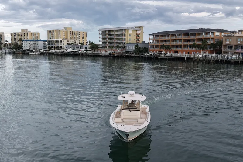 Slide: The Image of 2021 Grady-White Canyon 326 boat cruising near waterfront buildings under cloudy sky. - 34