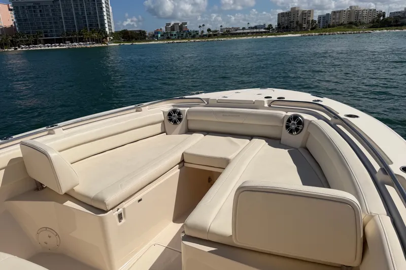 Slide: The Image of 2021 Grady-White Canyon 326 boat interior with beige seating, on calm water near a cityscape. - 45