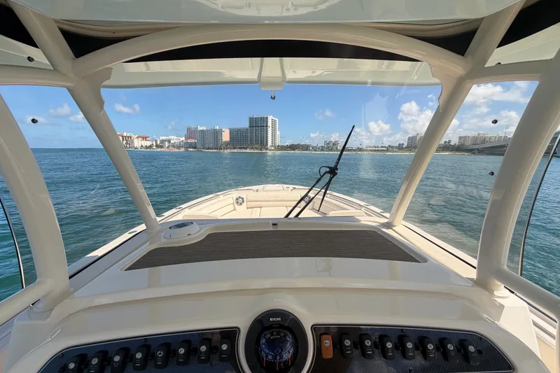 Slide: The Image of 2021 Grady-White Canyon 326 boat navigating coastal waters with city skyline view. - 70