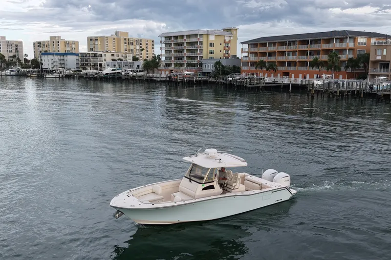 Slide: The Image of 2021 Grady-White Canyon 326 boat cruising near waterfront buildings under cloudy sky. - 38