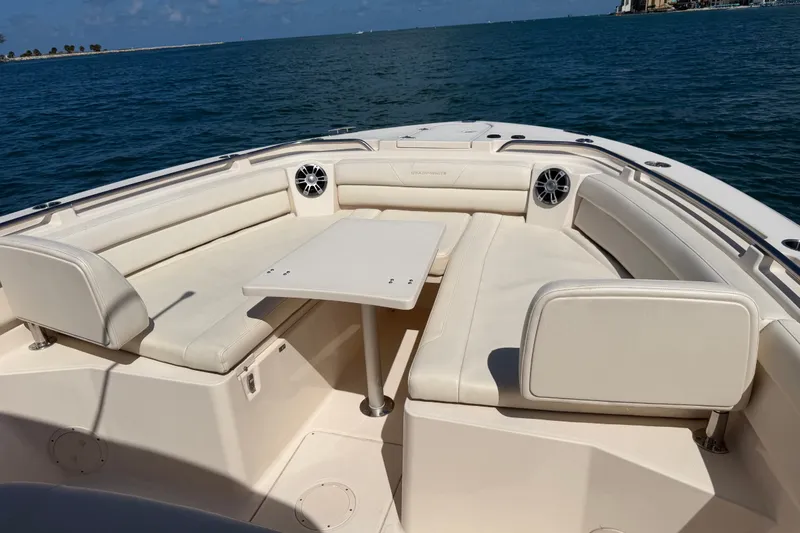 Slide: The Image of 2021 Grady-White Canyon 326 boat interior with cushioned seating and table on open water. - 53