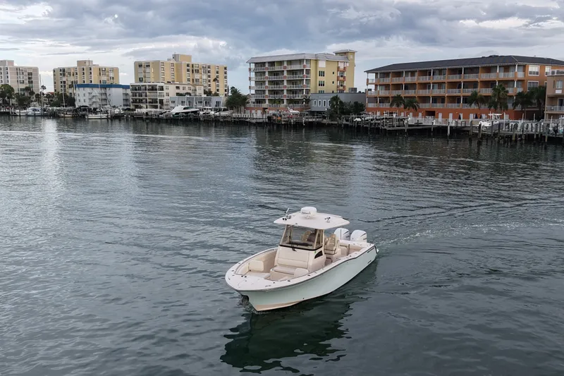 Slide: The Image of 2021 Grady-White Canyon 326 boat cruising near waterfront buildings under cloudy sky. - 36