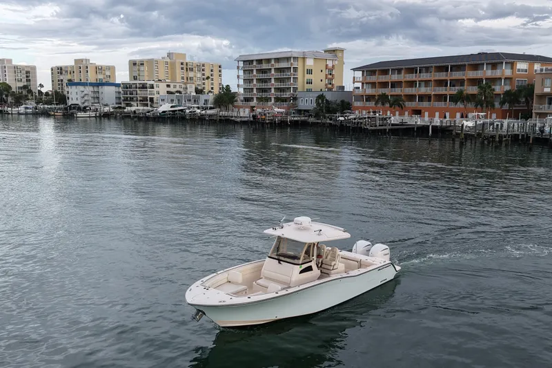 Slide: The Image of 2021 Grady-White Canyon 326 boat cruising near waterfront buildings under cloudy sky. - 35