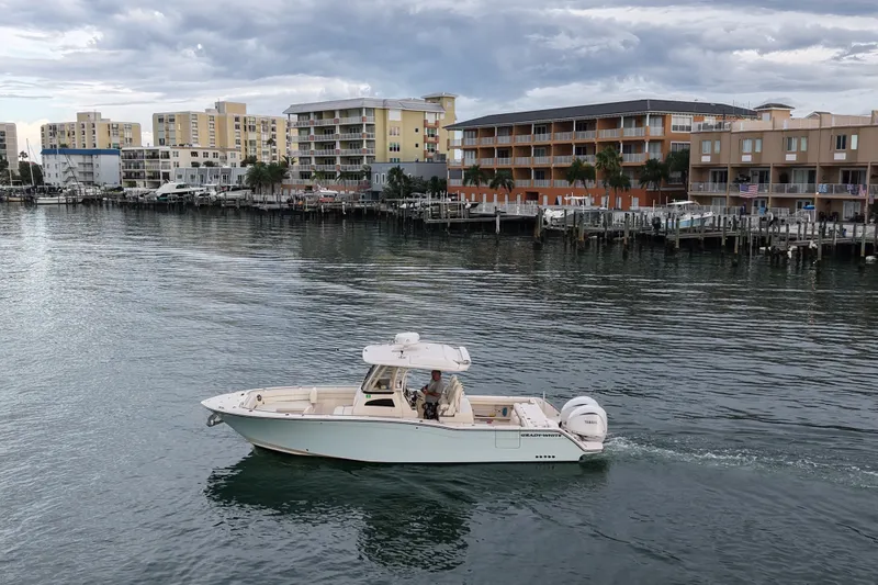 Slide: The Image of 2021 Grady-White Canyon 326 boat cruising near waterfront buildings under cloudy sky. - 40
