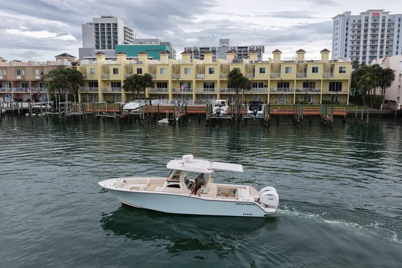 Slide: The Image of 2021 Grady-White Canyon 326 boat cruising near waterfront buildings. - 23