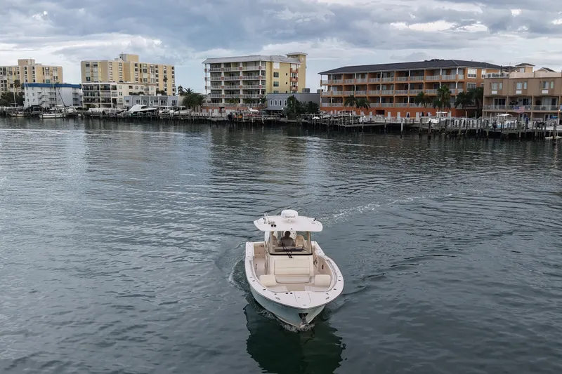 Slide: The Image of 2021 Grady-White Canyon 326 boat cruising near waterfront buildings under cloudy sky. - 33
