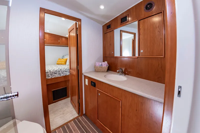Slide: The Image of The image shows a boat bathroom with wooden cabinets and a sink. A bedroom is visible in the background. - 36