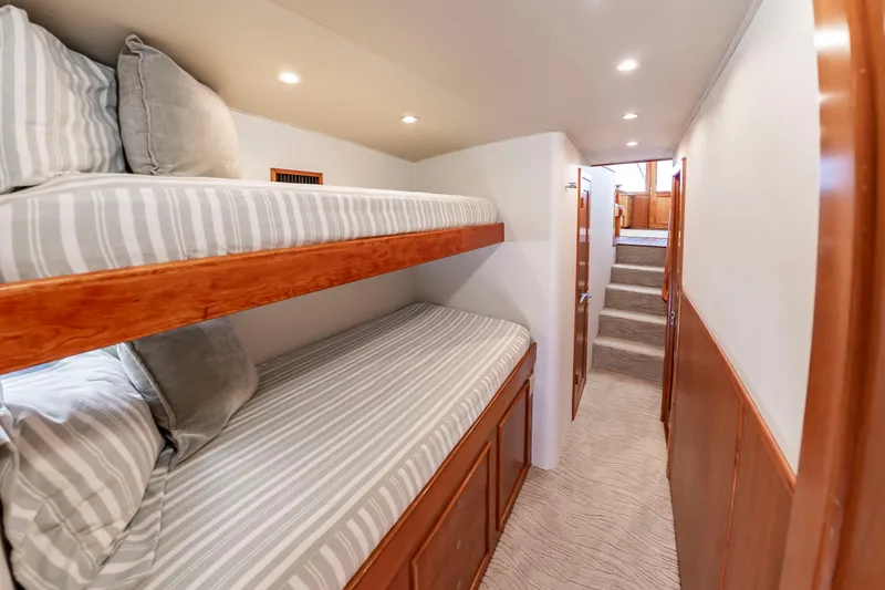 Slide: The Image of A cozy interior with bunk beds and striped bedding. A hallway leads to a staircase. - 38