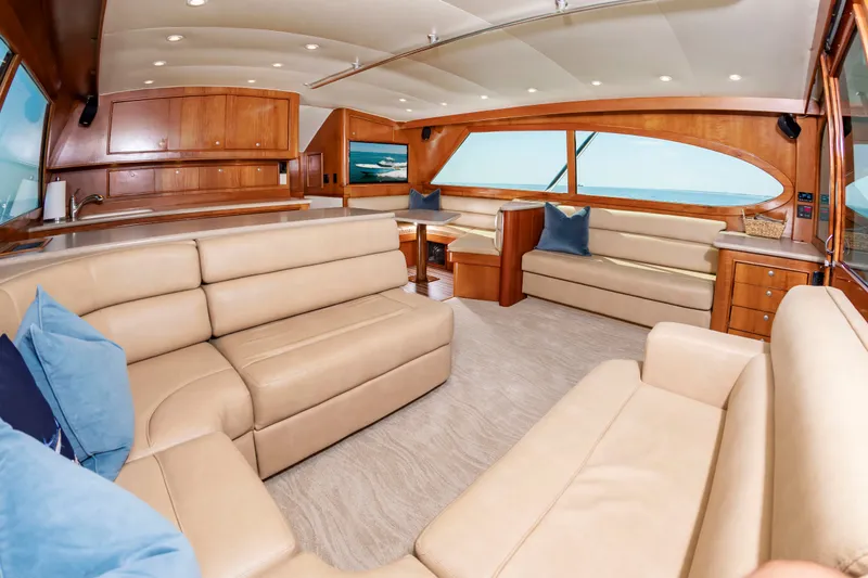 Slide: The Image of The image shows the interior of a 2004 Custom Carolina 61' Sportfisherman with beige leather sofas. - 23