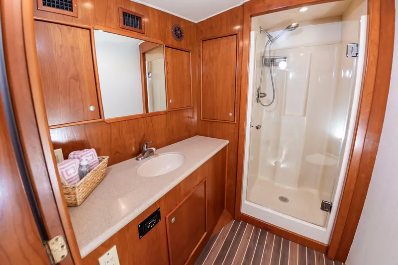 Slide: The Image of A sleek bathroom with wood paneling, sink, mirror, and a spacious shower. - 34