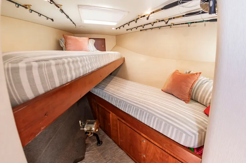 Slide: The Image of The cabin features two bunk beds with striped bedding and fishing rods mounted on the ceiling. - 44