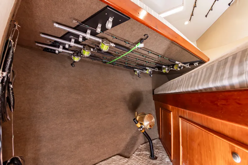 Slide: The Image of Fishing rods are neatly secured to the ceiling of a boat cabin, with wooden cabinetry below. - 48