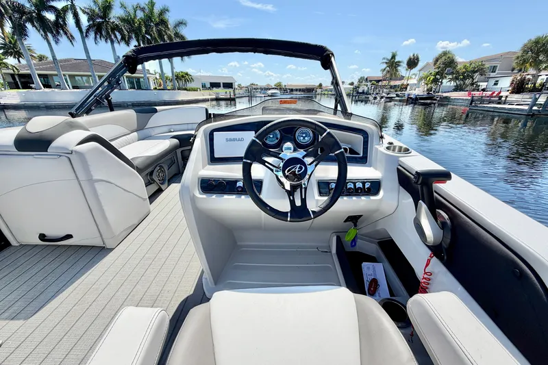 Slide: The Image of 2023 Avalon 2385 LSZ boat interior with steering wheel and dashboard on a sunny day. - 16