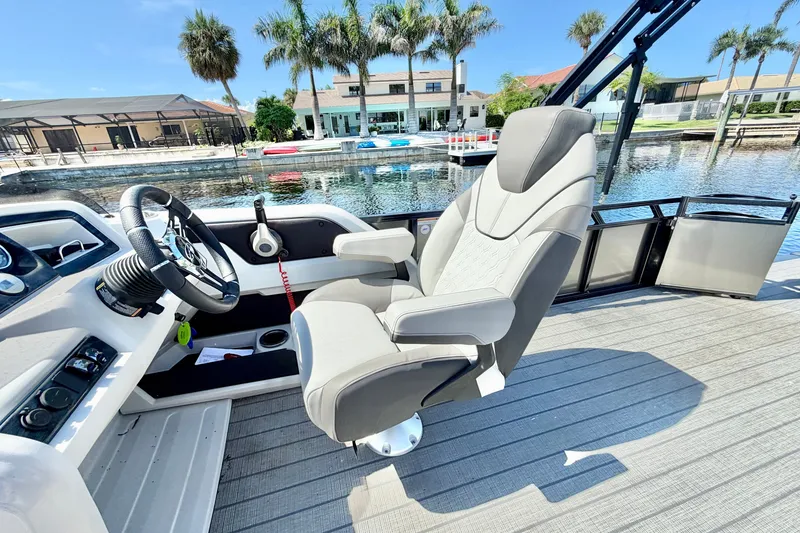 Slide: The Image of Captain's chair on 2023 Avalon 2385 LSZ boat, with waterfront view and palm trees. - 14