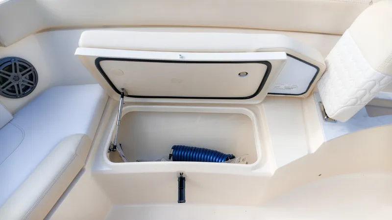 Slide: The Image of An open storage compartment on a Scout 240 XSF boat with a blue hose inside. - 16
