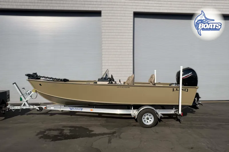 The Image of 2025 Lund 2075 Alaskan SS boat on trailer, parked outside a building. - 0