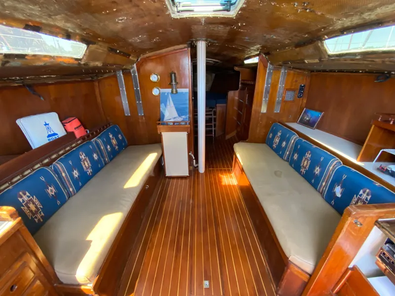Slide: The Image of Interior of a 1978 MSY 38 sailboat with wooden flooring and cushioned seating. - 16
