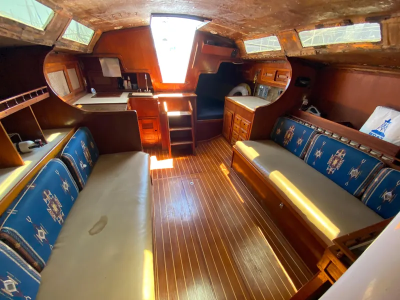 Slide: The Image of 1978 Sailboat MSY 38 interior with wooden finishes, blue cushioned seating, and natural light. - 32