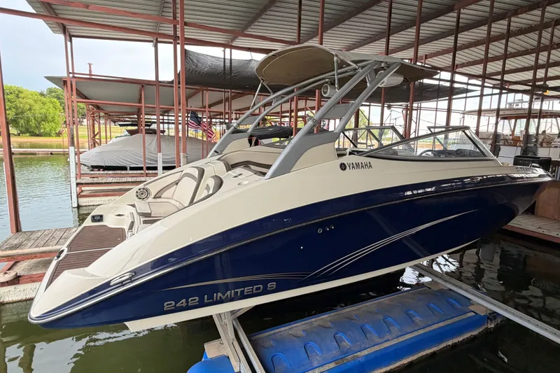 The Image of 2015 Yamaha Boats 242 Limited S in marina, sleek design, blue and white color scheme. - 2
