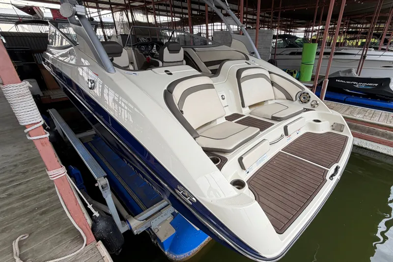 Slide: The Image of 2015 Yamaha Boats 242 Limited S in dock, showcasing sleek design and spacious seating. - 5