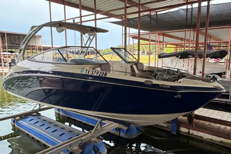 Slide: The Image of 2015 Yamaha Boats 242 Limited S in dock, blue and white exterior, covered marina setting. - 0