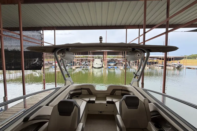 Slide: The Image of 2015 Yamaha Boats 242 Limited S docked in a marina, showcasing interior seating and canopy. - 26